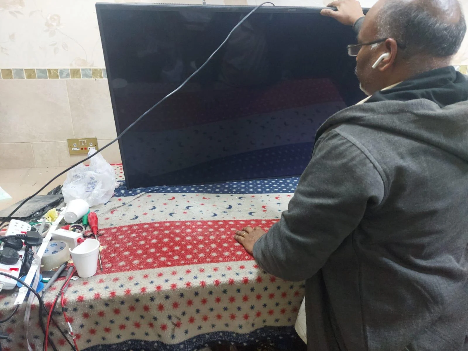فني يقوم بفحص وتصليح شاشة تلفزيون